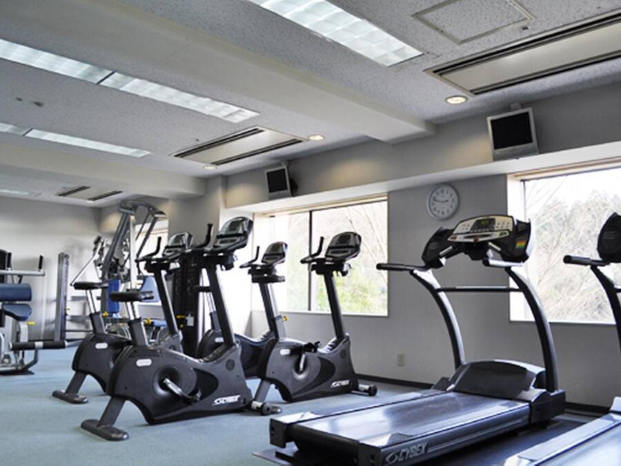 Un gimnasio con cintas de correr, elípticas y equipo de pesas.