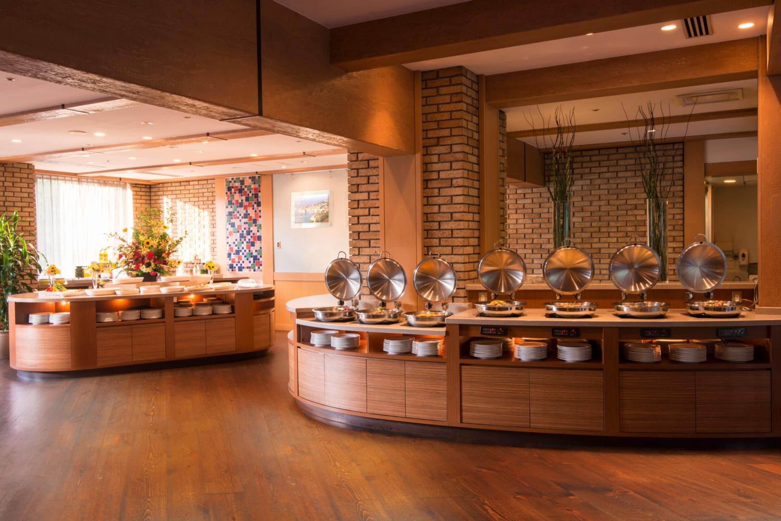 Un'area buffet con diverse postazioni di servizio, una parete in mattoni e un pavimento in legno.