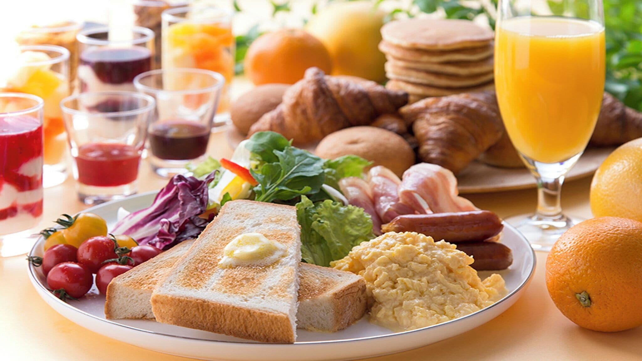 Un piatto per la colazione con pane tostato, uova, salsiccia e insalata.