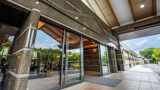 A modern building entrance with large glass doors, stone pillars, and a covered walkway. - International Garden Hotel Narita (Narita)