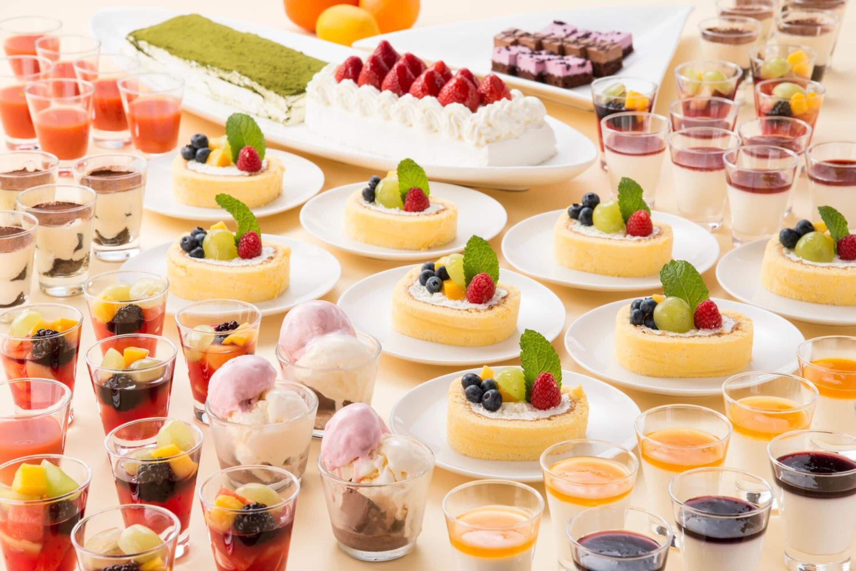 Diversos postres como pasteles, tartas y parfait de frutas, presentados en platos y vasos.
