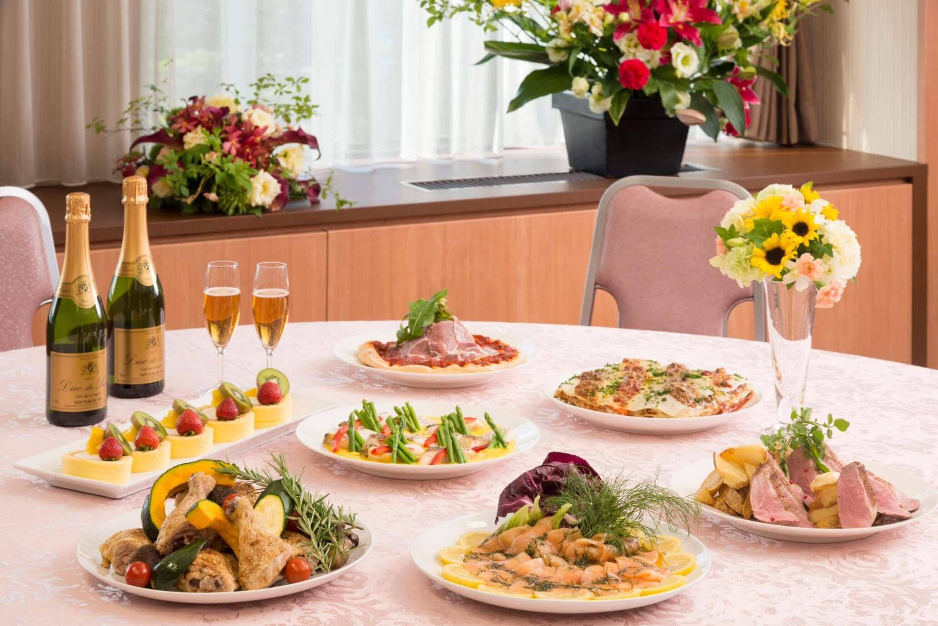 Een eettafel met verschillende gerechten, drankjes en een bloevas.