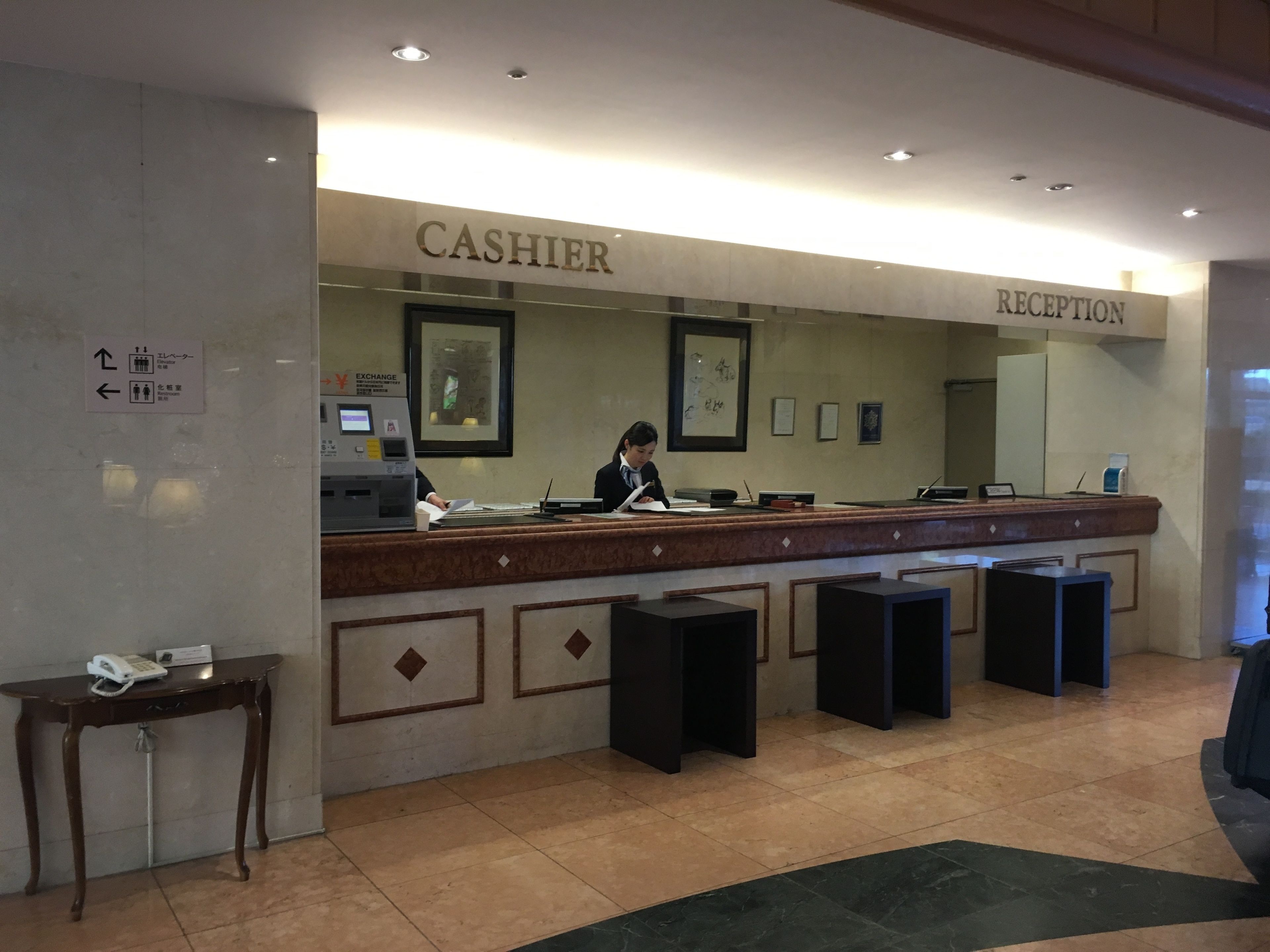 A reception desk with a cashier and a reception area. There is an ATM machine to the left of the cashier.