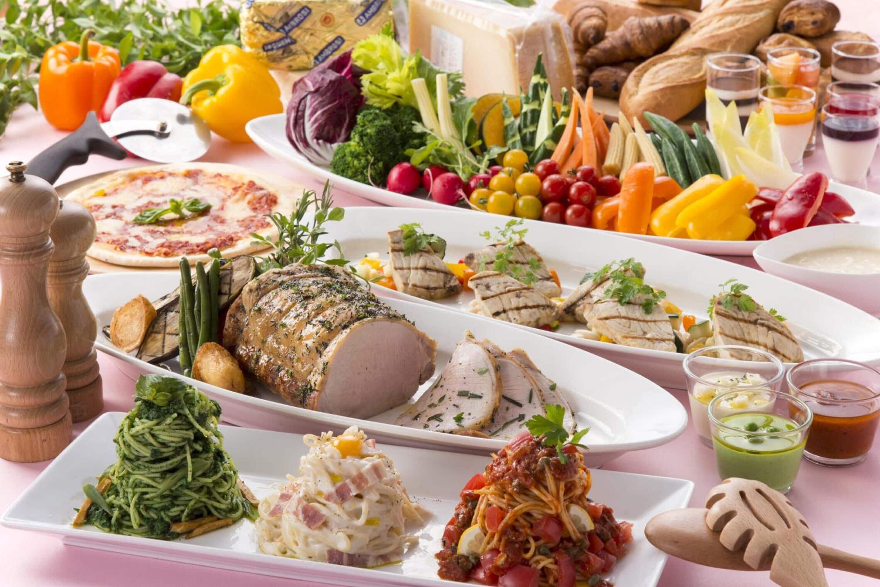 Variedad de platos, entre ellos un pollo asado, pizza y diferentes opciones de pasta, que sugieren una amplia selección de comidas.