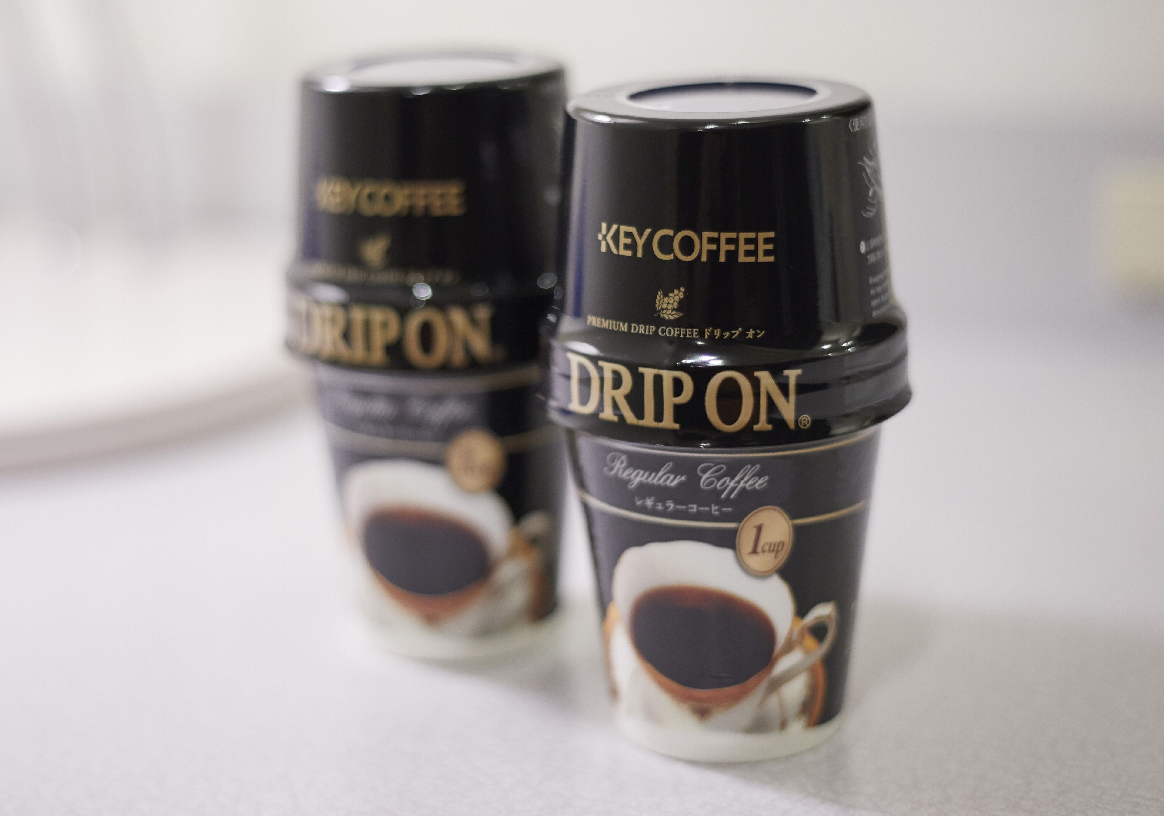 Dos recipientes de café de goteo con la etiqueta 'Key Coffee' e indicación de tamaño '1 taza'.