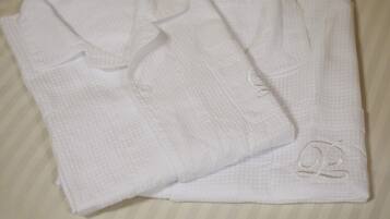 Two neatly folded white towels with embroidered initials on a striped bedspread.