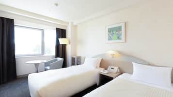 Una habitación de hotel con dos camas, un escritorio, una silla, una lámpara y un cuadro en la pared.