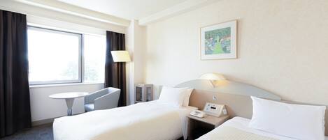 Ein Hotelzimmer mit zwei Betten, einem Schreibtisch, einem Stuhl, einer Lampe und einem Bild an der Wand.