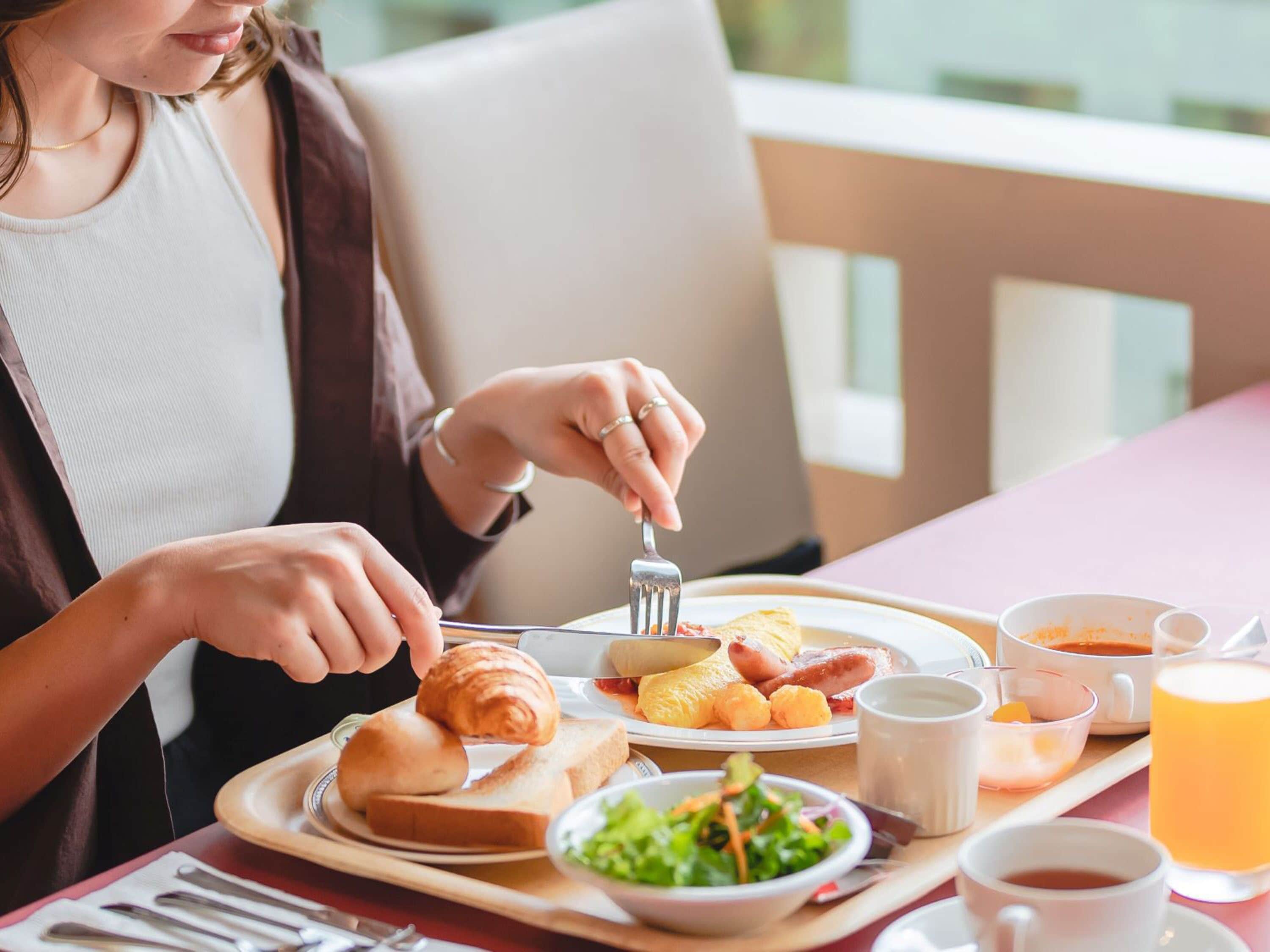 Bandeja de desayuno con cruasanes, tostadas, huevos, salchichas y una ensalada.
