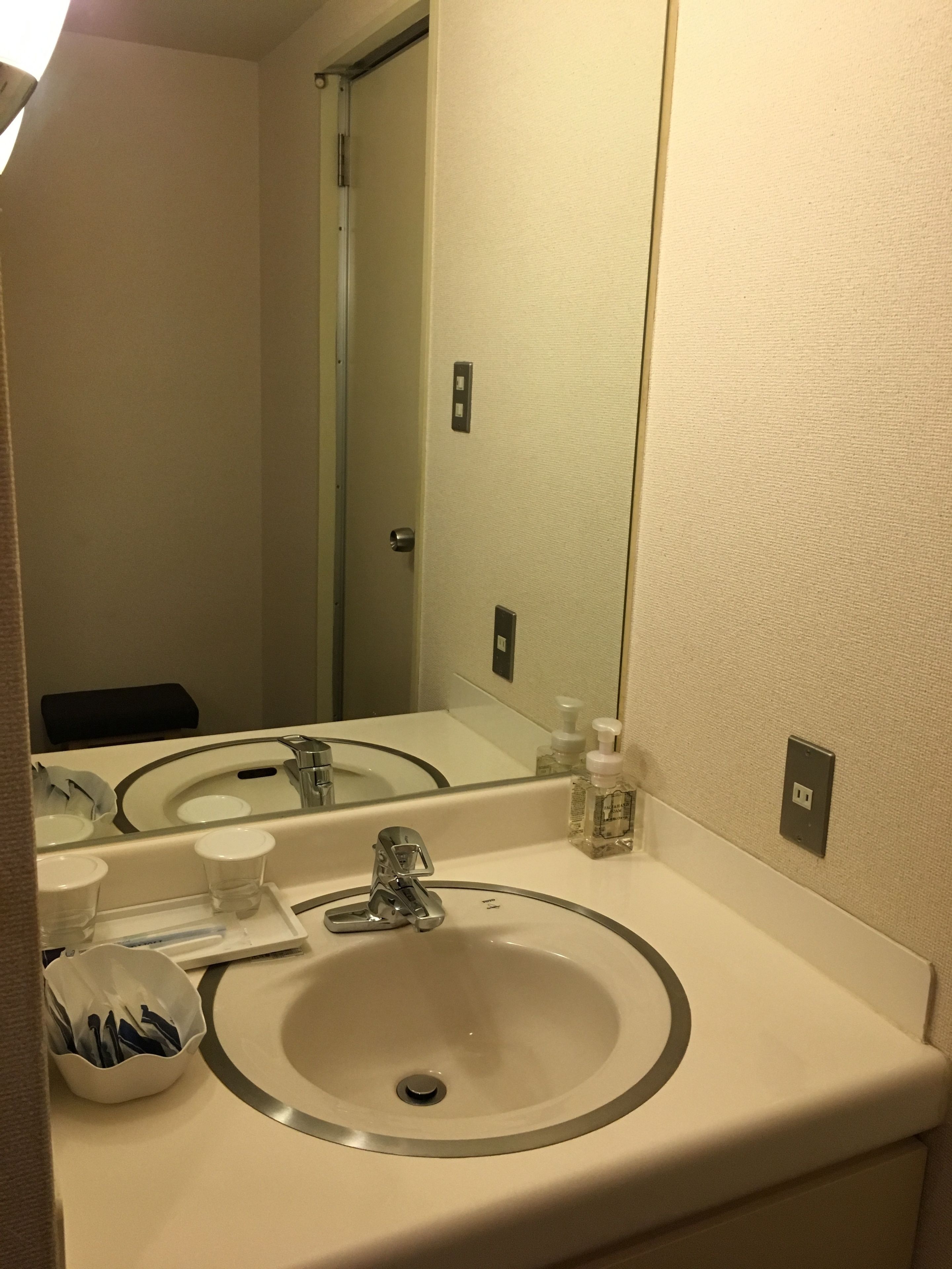 A bathroom with a sink, mirror, and toiletries.
