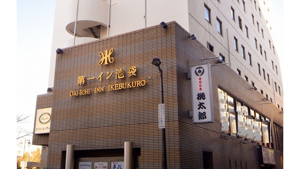 Un hotel alto con una fachada distintiva en blanco y beige, que cuenta con varios balcones a la izquierda.