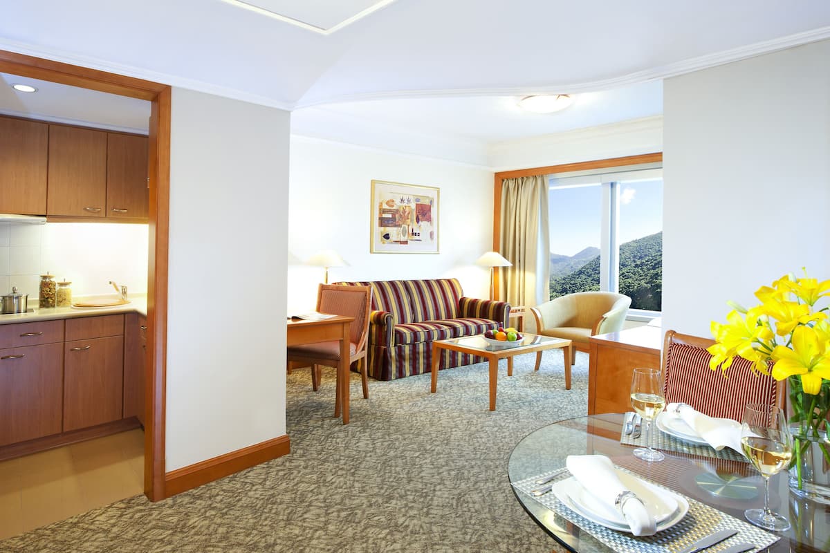 Een hotelkamer met een eethoek, een bank, een stoel en uitzicht op de bergen.