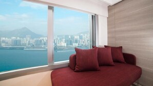 Una habitación moderna con un amplio ventanal que ofrece vistas a la ciudad, un sofá rojo y una pared de madera.