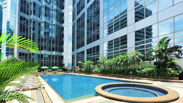 Un edificio moderno con piscina y sillones de descanso.