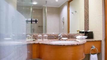 A modern bathroom with a large mirror, a granite countertop sink, a towel rack, and a shower area.