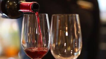 A person pouring red liquid into a wine glass.