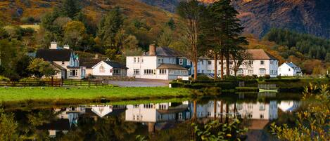 A lakeside property with multiple buildings, a dock, and a reflection in the water.