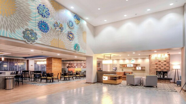 Un vestíbulo amplio con mostrador de recepción, zona de estar y decoración mural.