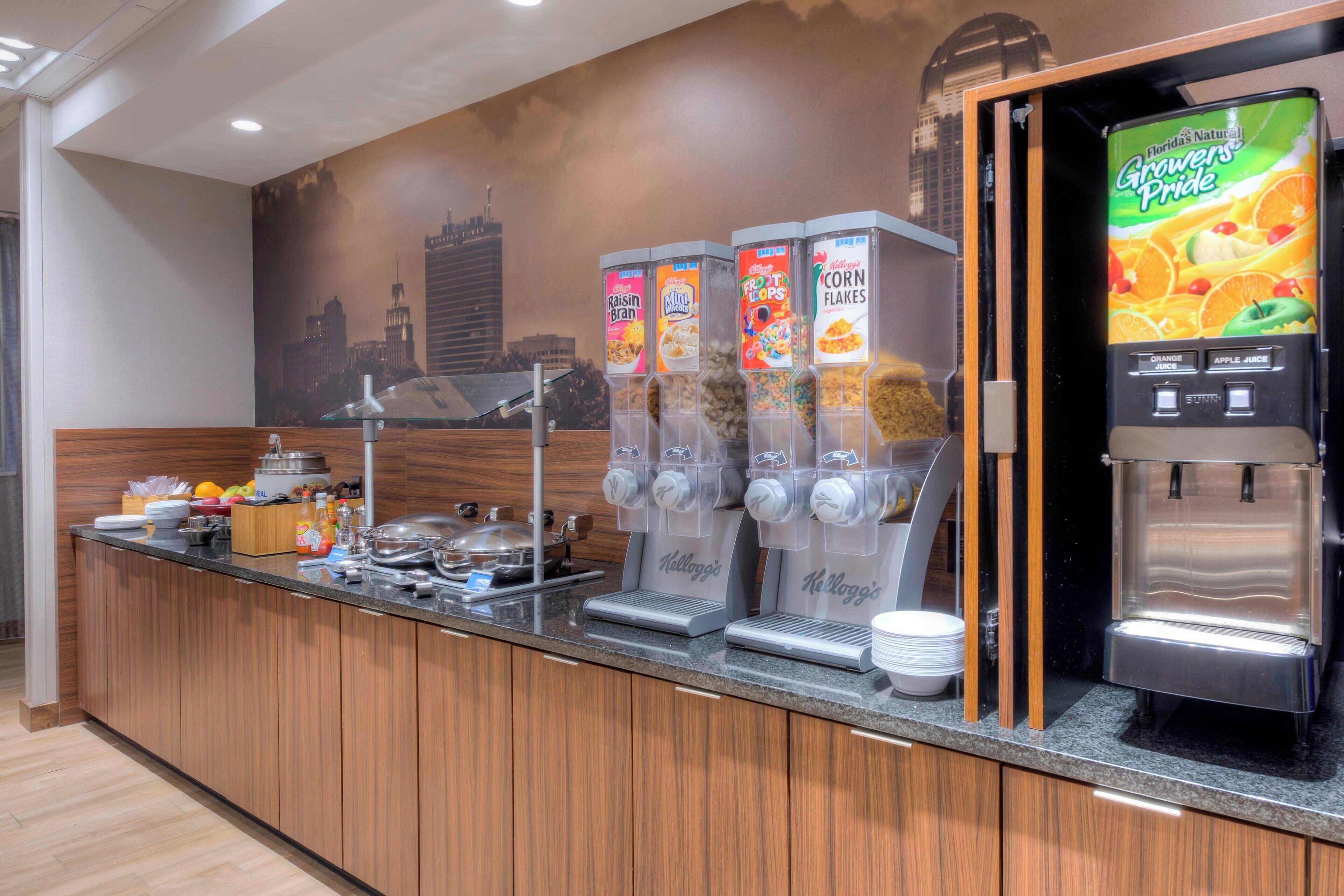 Una barra de l'esmorzar amb diversos dispensadors de begudes, incloent suc d'aranja i suc de poma, i una cafetera.