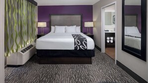 A hotel room with a large bed, two bedside tables with lamps, a mirror, and a walk-in closet.