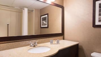 A bathroom with a large mirror, a sink, and a toilet.