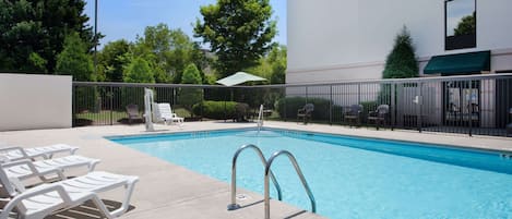 Piscina com espreguiçadeiras e cerca.