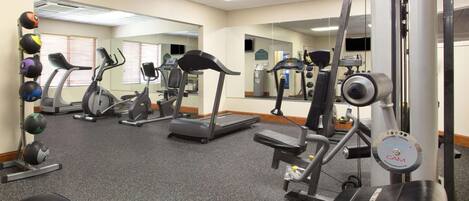 Une salle de sport équipée de tapis de course, de vélos elliptiques et de matériel de musculation.