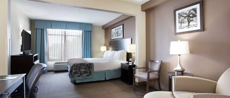 A hotel room with a bed, desk, chair, and a TV.