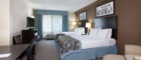 A hotel room with a large bed, two bedside tables, a desk with a chair, a television, and a window with curtains.