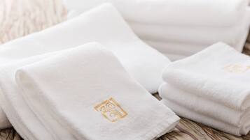 Neatly folded white towels with a logo on a wooden surface.