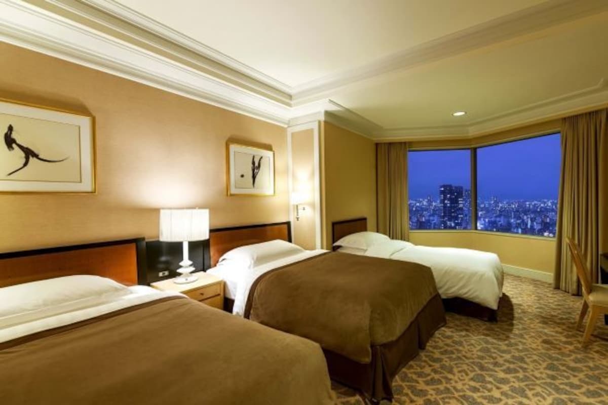 Habitación de hotel con dos camas, vistas a la ciudad y obras de arte en las paredes.