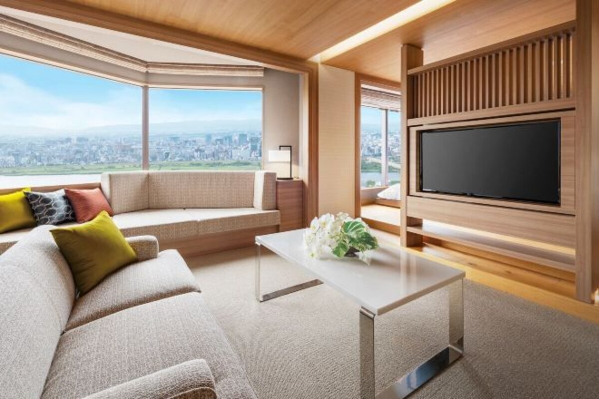 A modern living room with a sofa, a coffee table, and a TV mounted on the wall.
