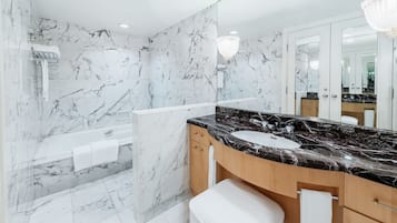 A modern bathroom with a marble wall, a black marble sink, and a glass-enclosed shower.