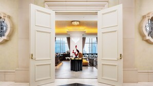 A hotel lobby with a central reception desk, large windows, and a black and white tiled floor. - Hotel Hankyu International (Osaka)
