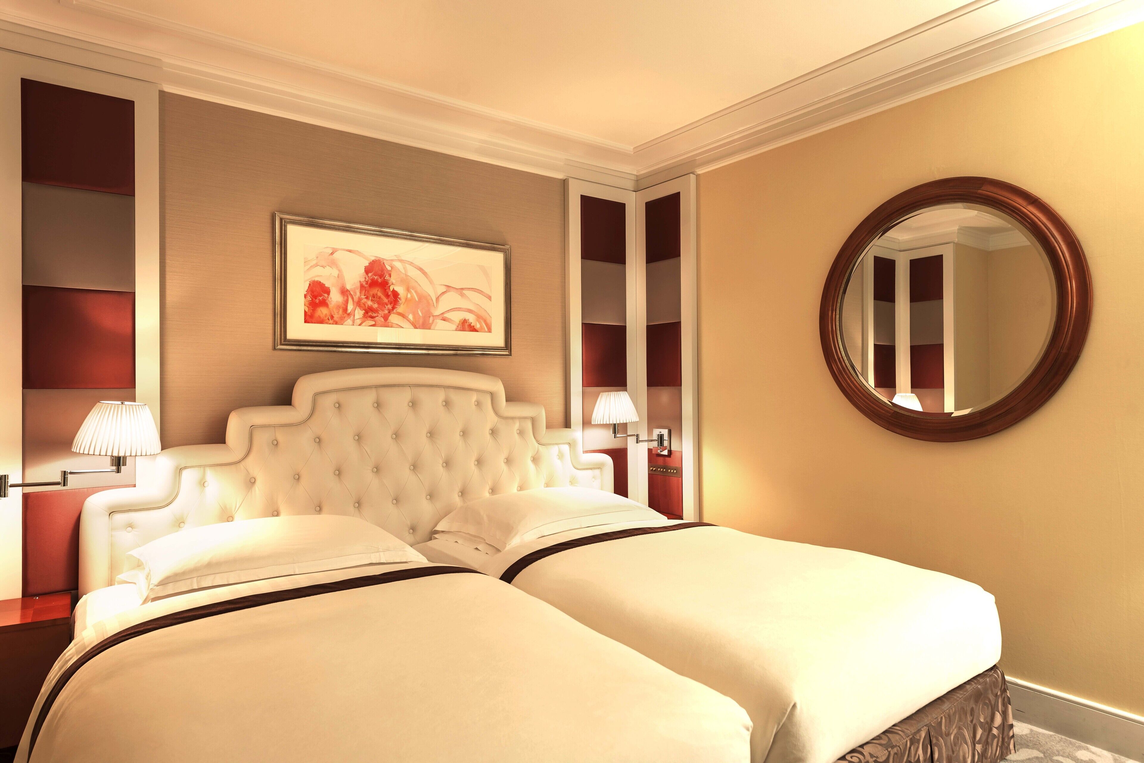 A hotel room with a large bed, a round mirror, and a framed picture on the wall.