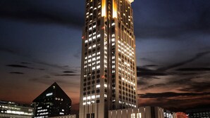 A tall, illuminated skyscraper with a modern design, featuring numerous windows and a prominent corner light. - Hotel Hankyu International (Osaka)
