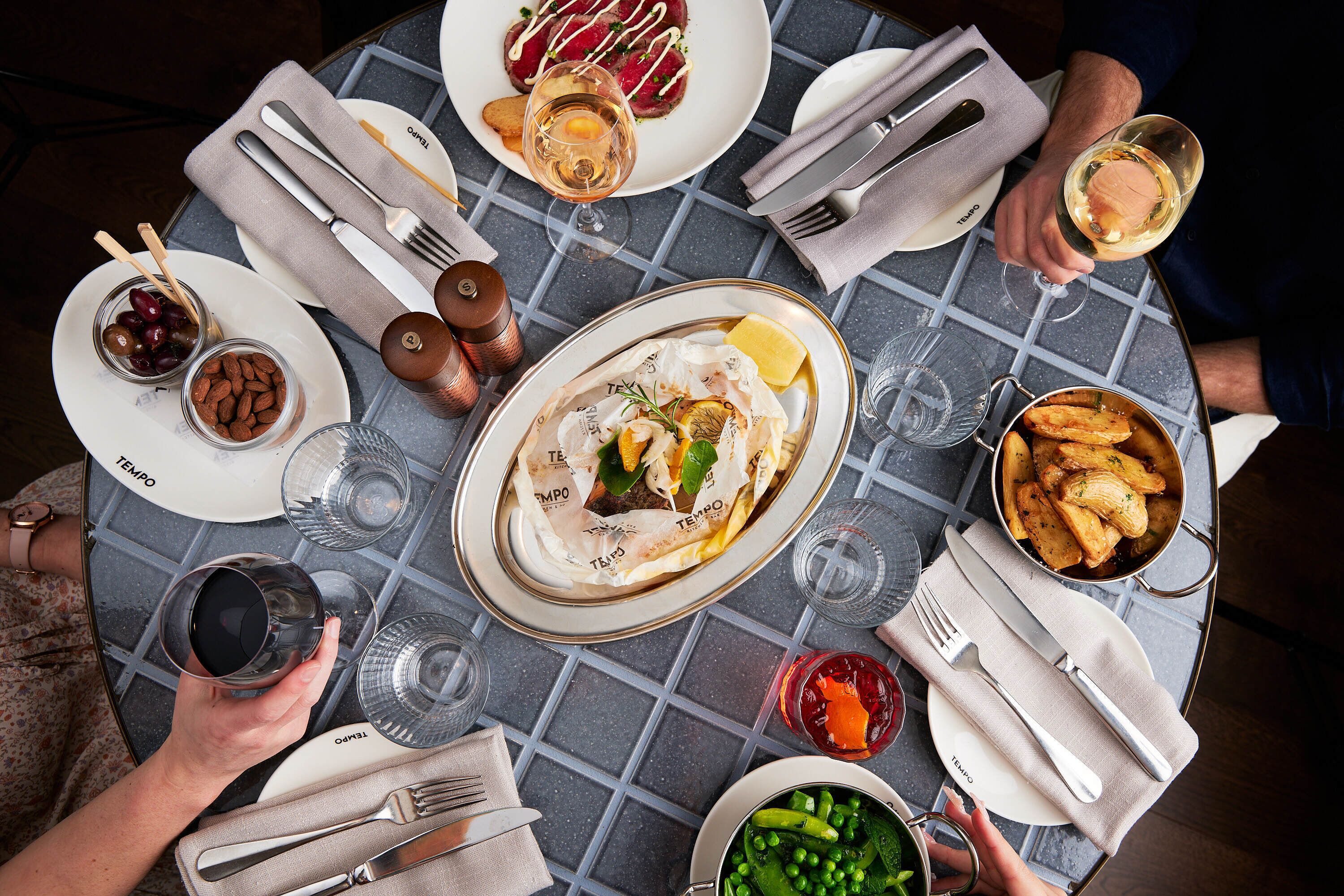A round dining table with plates of food, glasses, and cutlery.