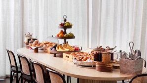 Un bufé de desayuno con diversas bollerías, frutas y salsas sobre una mesa de madera.