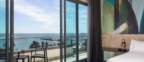 Habitación de hotel con un balcón grande, una cama, un cuadro y vista al mar.
