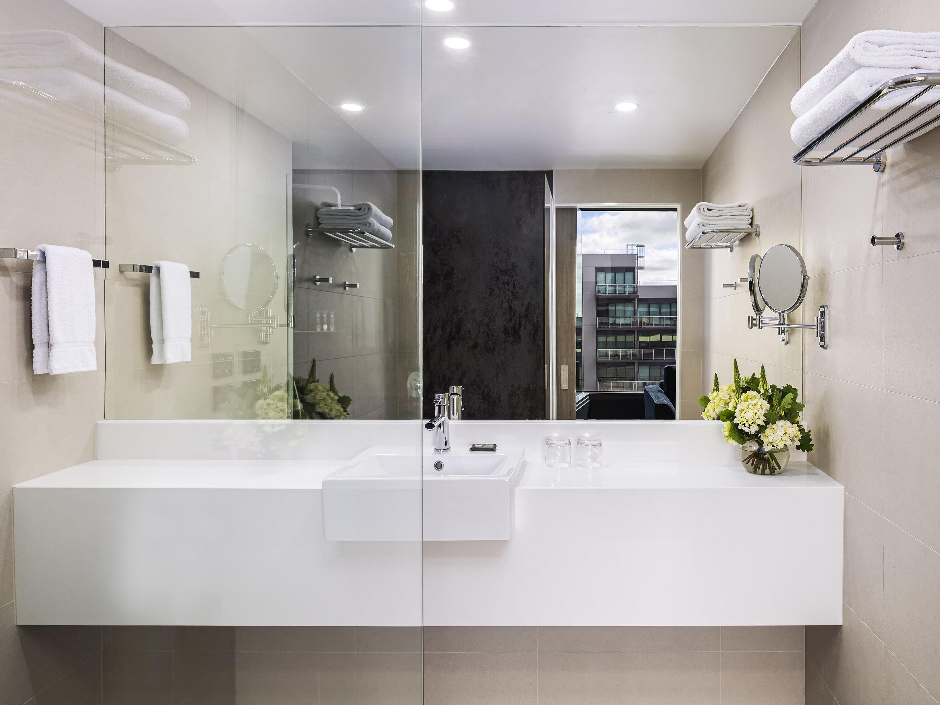 Un bagno moderno con cabina doccia in vetro, uno specchio grande e un mobile lavabo.