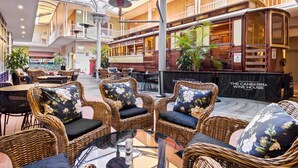A spacious indoor area with wicker furniture, a glass table, and a tram-like structure. - Quality Hotel Dickson (Dickson)