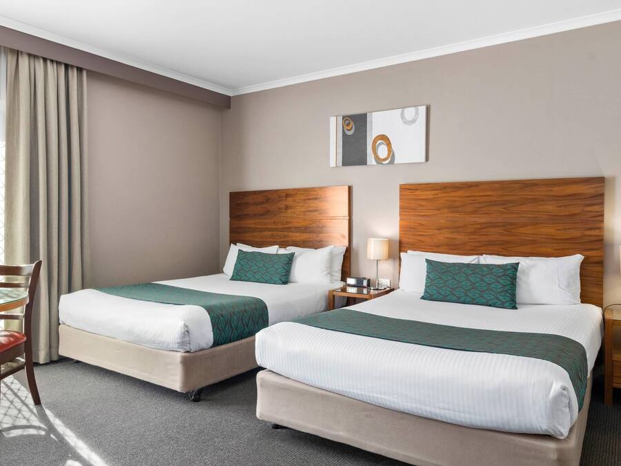 Habitació d'hotel amb dos llits, un escriptori i una cadira.