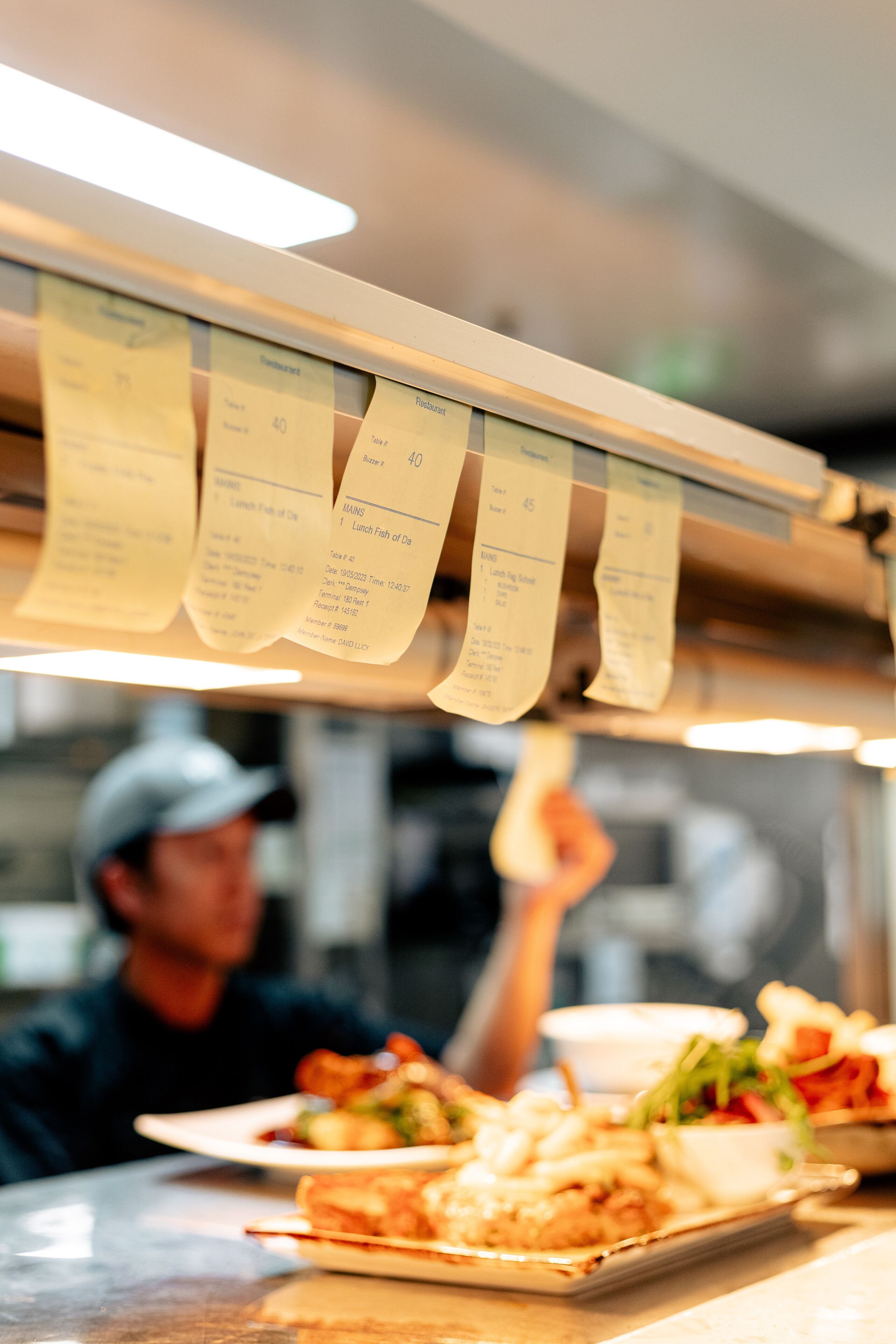 Un comptoir de restaurant où plusieurs commandes sont affichées sur un menu suspendu.