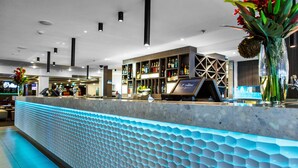 A modern bar area with a marble counter, a variety of liquor bottles, and a decorative vase with flowers. - Quality Hotel Dickson (Dickson)