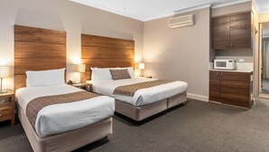 A hotel room with two beds, a microwave, a cabinet, and a nightstand with a lamp. - Quality Hotel Dickson (Dickson)