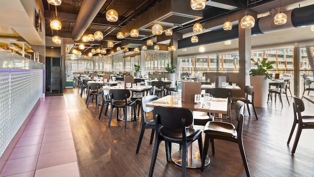 A modern restaurant interior with multiple dining tables, chairs, pendant lighting, and large windows. - Quality Hotel Dickson (Dickson)