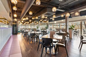 A modern restaurant interior with multiple dining tables, chairs, pendant lighting, and large windows. - Quality Hotel Dickson (Dickson)