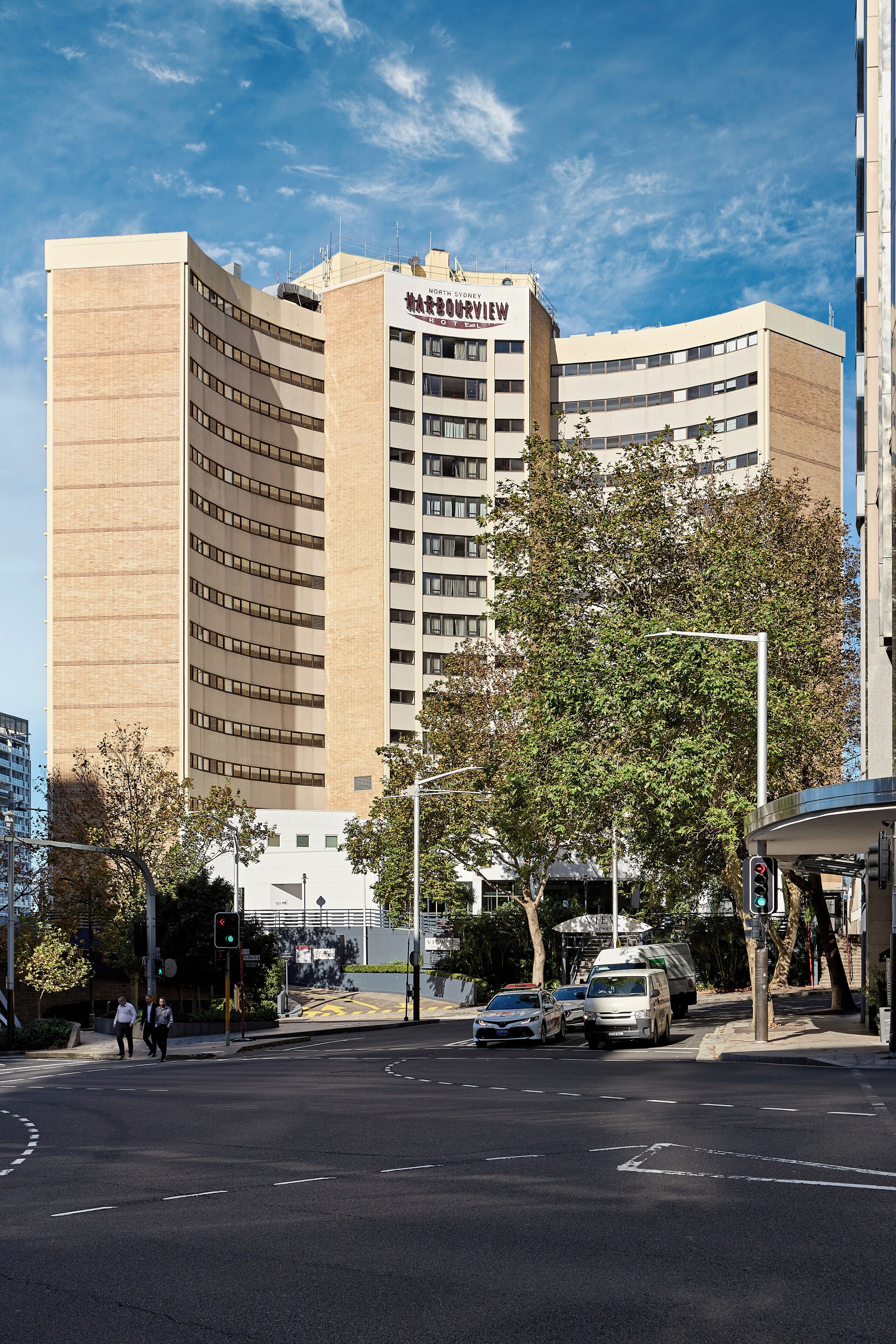 Un hotel alto de varios pisos, con fachada curva y un letrero llamativo.