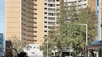 Un hotel alto de varios pisos, con fachada curva y un letrero llamativo.