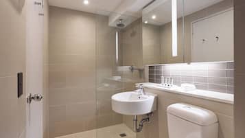 A modern bathroom with a glass shower enclosure, a white sink, and a toilet.